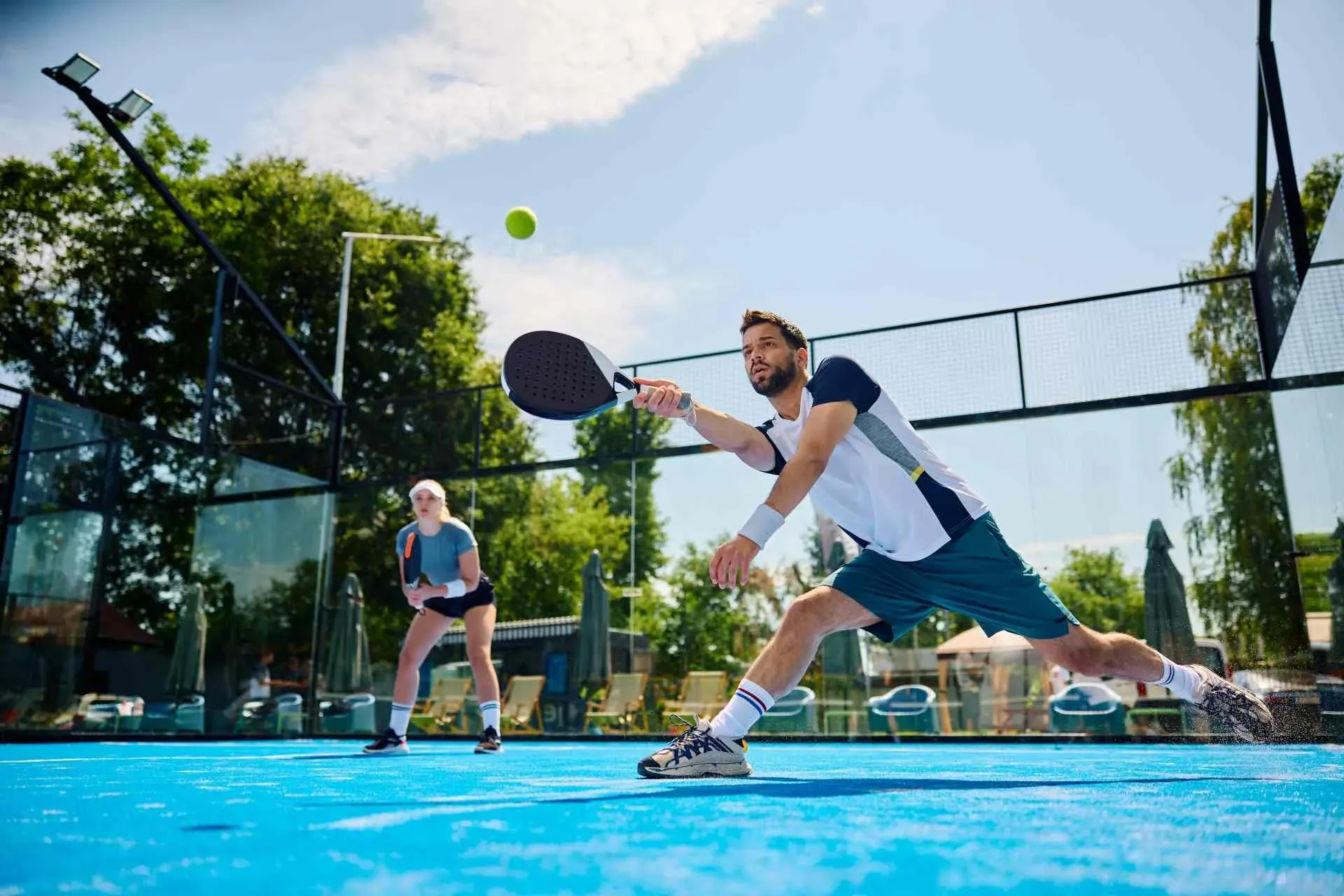 Padel player stretching for a forehand during a doubles match